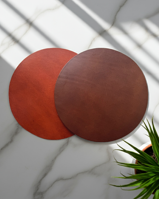 Two leather mouse mats on a white marble background.