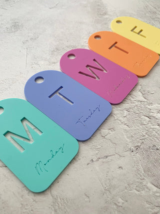 Colourful day of the week tags on a textured surface