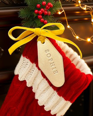 A gold label attached to a Christmas stocking with the name Sophie stamped in it.