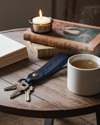 Candle, books, mug of tea, and keychain on a wooden table