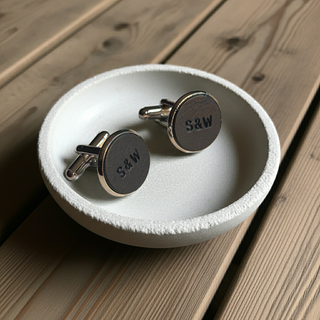 Navy Cufflinks with 'S&W' engraving on a white dish on a wooden surface