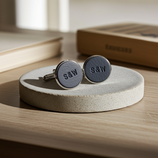 Pair of cufflinks with 'S&W' engraving on a wooden surface