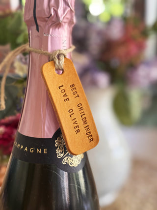 Bottle of champagne with a yellow leather decorative tag on a blurred floral background