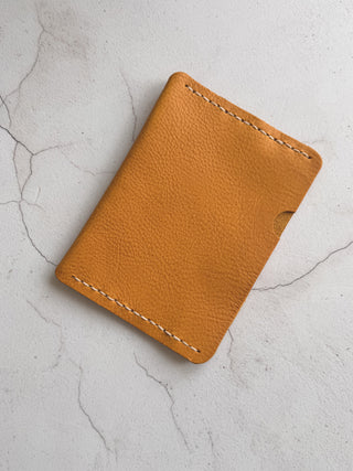 yellow leather passport case wallet on a light gray textured surface